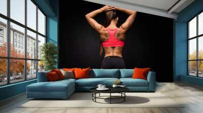 Rear view of a fit strong young woman with a muscular toned body wearing sportswear looking to the side, on grey background Wall mural